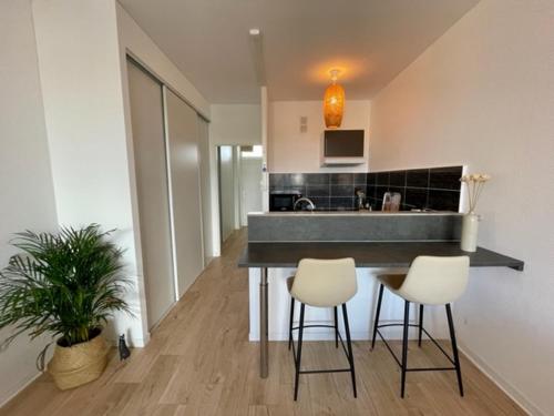 eine Küche mit zwei Hockern und einer Theke in einem Zimmer in der Unterkunft Lumineux Studio 30m2 / Balcon / Proche Gare et Ville in Montigny-lès-Metz