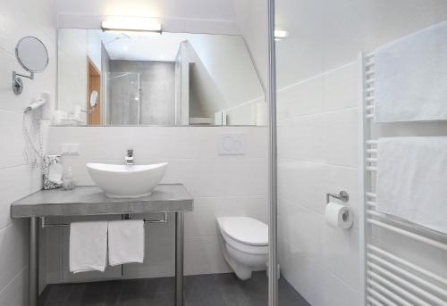 a white bathroom with a sink and a toilet at Parkhotel Flora in Bad Grund