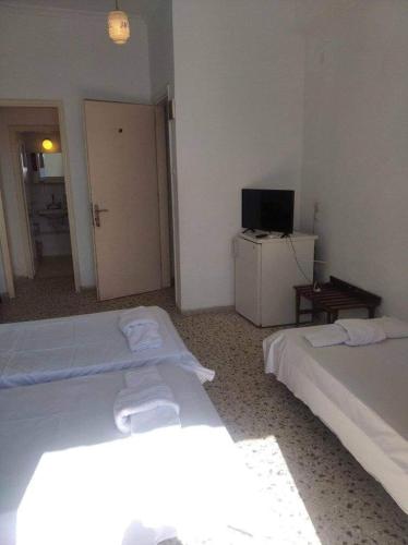 a room with two beds and a television in it at Ammoudia Rooms in Agia Marina Aegina