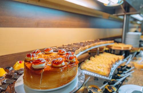a cake with cherries on top on a counter with other pastries at Kaliakra Beach Hotel - Ultra All Inclusive in Albena