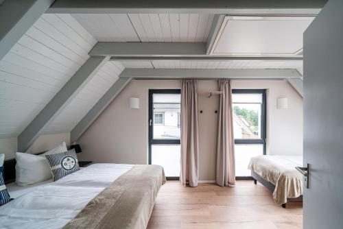een slaapkamer op zolder met 2 bedden en een raam bij Hagebutte- Domizil am Ostseewald in Zingst