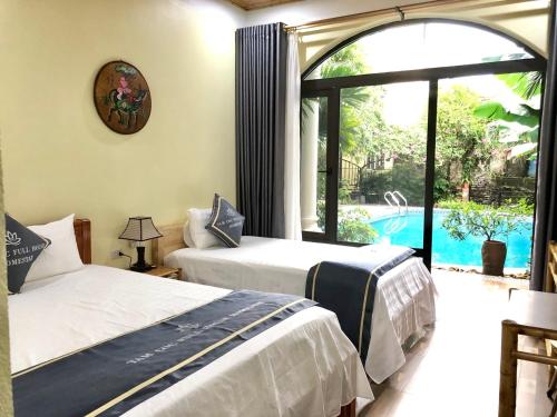 two beds in a room with a view of a pool at Tam Coc Full House Homestay in Ninh Binh