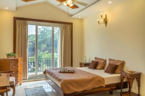 a bedroom with a bed and a large window at StayVista at Dhauladhar House - Luxurious Chateau in Kangra in Dharamshala