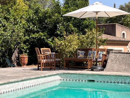 una piscina con ombrellone, tavolo e sedie di Chambre indépendante avec terrasse privée et piscine a Nîmes