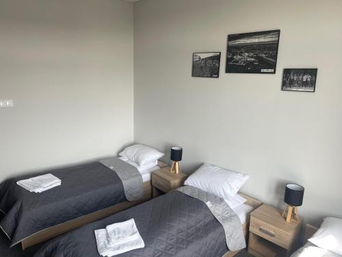 two beds in a room with pictures on the wall at AQUARA Radomsko in Radomsko