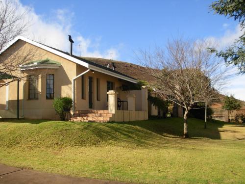 a white house with a tree in the yard at Thaba Tsweni Lodge & Safaris in Graskop