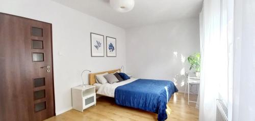 a bedroom with a bed with a blue blanket at ApartamentyPrzyMorzu Centrum Blisko Plaży in Kołobrzeg