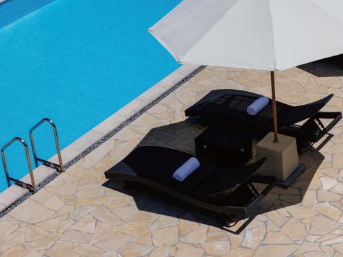 two chairs with an umbrella next to a swimming pool at ホーム ステイ ユミハ 沖縄 by バンヤン グループ in Onna