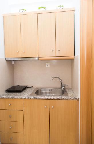 a kitchen with a sink and wooden cabinets at marietta city center apartments Nafplio in Nafplio