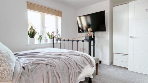 a bedroom with a bed and a tv on a wall at Entire home: Bicester Village 10min walk (650m) in Bicester
