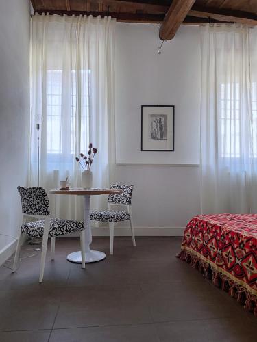 a white room with a table and chairs and a bed at Alkimia Smart Rooms in Ferrara