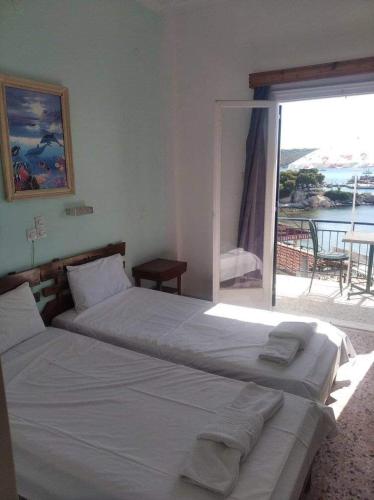a bedroom with two beds and a view of a balcony at Ammoudia Rooms in Agia Marina Aegina