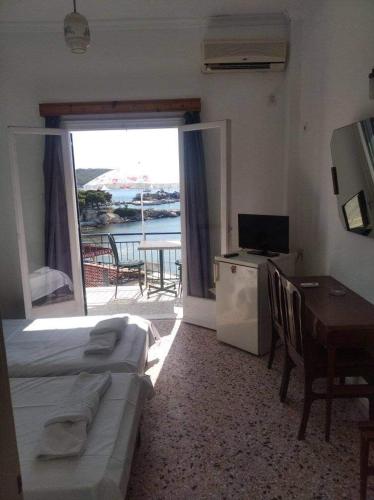 a hotel room with two beds and a table and a balcony at Ammoudia Rooms in Agia Marina Aegina