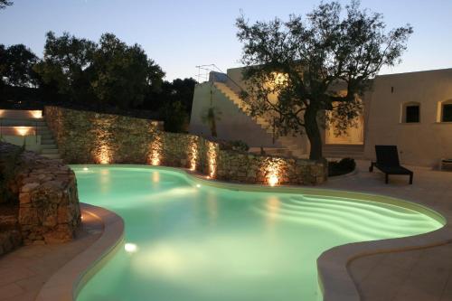 a swimming pool with lights in a backyard at night at Tenuta Aphrodite in Racale