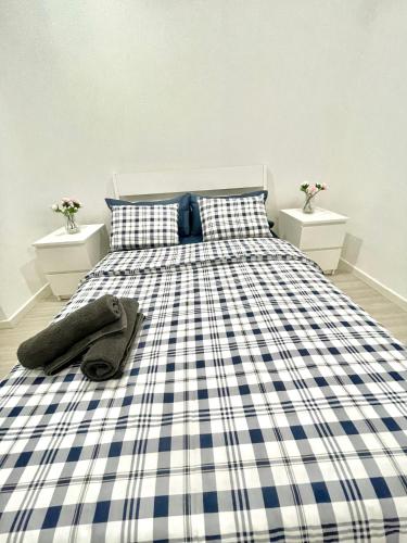 ein Bett mit einer blau-weißen karierten Decke und zwei Nachttischen in der Unterkunft Lisboa New in Bobadela