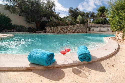 a pool with two towels and two glasses of wine at Tenuta Aphrodite in Racale