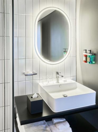 a white bathroom with a sink and a mirror at The Rockefeller Hotel by NEWMARK in Cape Town