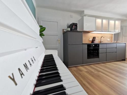 a living room with a piano and a kitchen at Neues City Center Piano Appartement mit Netflix in Klagenfurt