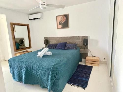 a bedroom with a bed with a blue blanket and a mirror at Villa cocoon sur la plage in Baie Nettle