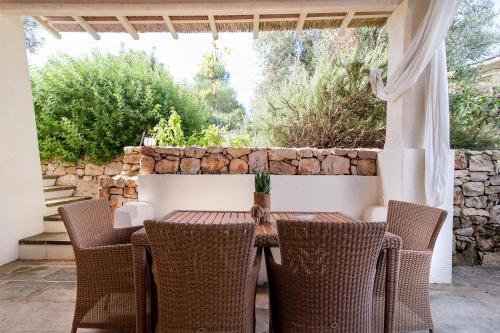 a table and chairs on a patio with a stone wall at Tenuta Aphrodite in Racale