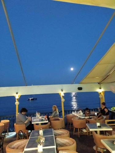 a group of people sitting at tables on a cruise ship at Ammoudia Rooms in Agia Marina Aegina