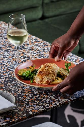 a plate of food on a table with a glass of wine at The Rockefeller Hotel by NEWMARK in Cape Town