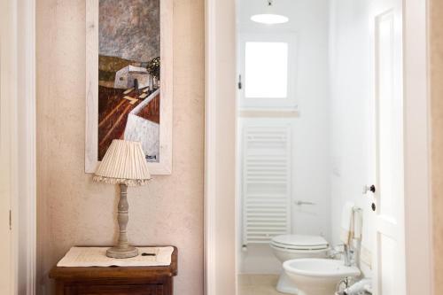 a bathroom with a toilet and a lamp on a table at Tenuta Aphrodite in Racale