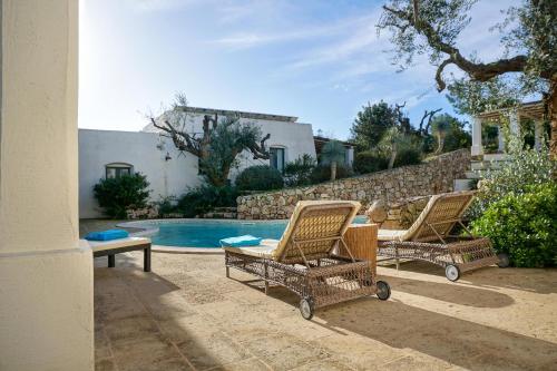 two chairs and a table next to a swimming pool at Tenuta Aphrodite in Racale
