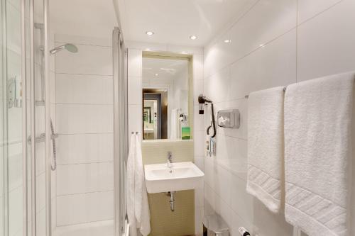 y baño blanco con lavabo y ducha. en MEININGER Hotel Wien Downtown Franz en Viena