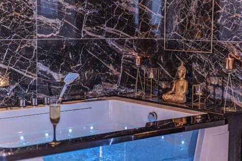 a bath tub in a bathroom with a marble wall at Magnifique loft / spa en face de la cathédrale ! in Narbonne
