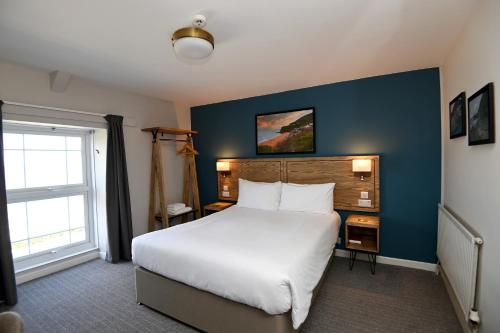 a bedroom with a large white bed and a blue wall at Ship Inn in Aberporth