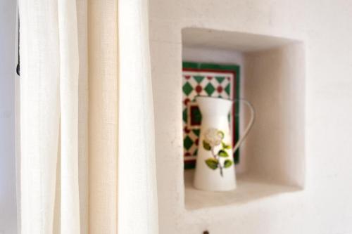 a white vase sitting on a shelf next to a window at Tenuta Aphrodite in Racale