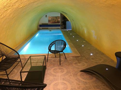 une piscine avec deux chaises et une table dans l'établissement LA VILLA CAPUCINE, à Vinay