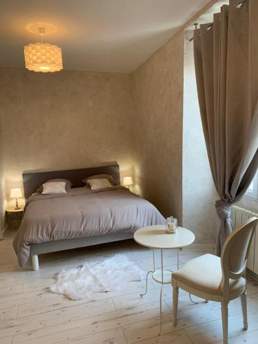 ein Schlafzimmer mit einem Bett, einem Tisch und einem Stuhl in der Unterkunft LA VILLA CAPUCINE in Vinay