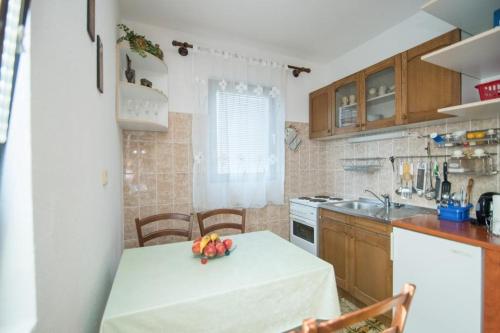 eine Küche mit einem Tisch und einer Obstschale darauf in der Unterkunft Apartments Nataša in Supetar