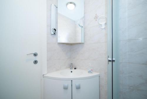 a white bathroom with a sink and a shower at Apartments Nataša in Supetar