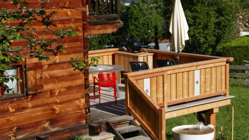 une terrasse avec un bain à remous et un parasol dans l'établissement Chamonix petit chalet Cocooning, à Servoz