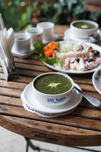 een tafel met een kom soep en een bord eten bij Tea Valley Resort, Munnar in Munnar