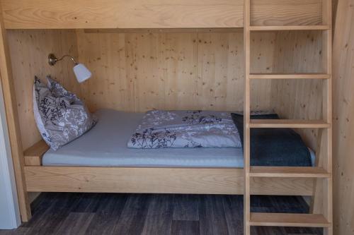 Ce lit se trouve dans un dortoir doté de lits superposés en bois. dans l'établissement Tiny-House mit großer Terrasse zum Genießen!, 