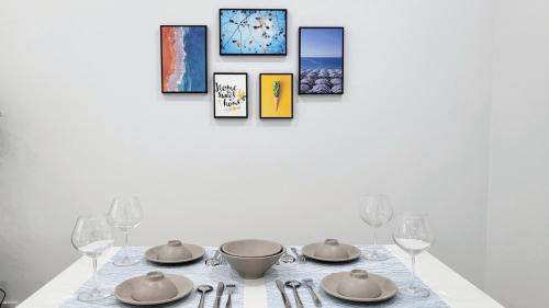 a dining room table with plates and glasses and paintings at Bcons Garden Luxury Aparment in Dĩ An