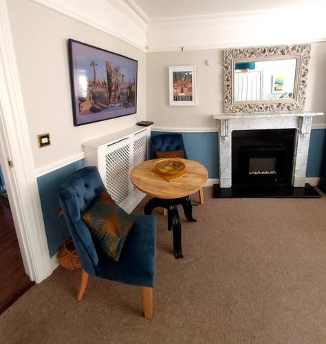 a living room with a table and a fireplace at Beautifully appointed, period seaside apartment in Folkestone