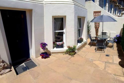 a patio with a table and chairs and an umbrella at Beautifully appointed, period seaside apartment in Folkestone