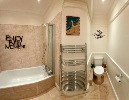 y baño con bañera, aseo y lavamanos. en Beautifully appointed, period seaside apartment en Folkestone