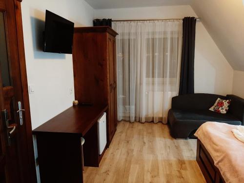 Una pequeña sala de estar con un sofá y un televisor. en Villa Krzesanica, en Czarna Góra