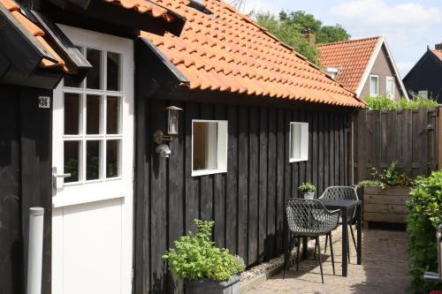 um barracão preto com uma porta branca e cadeiras em B&B Woudzicht em Oudeschoot