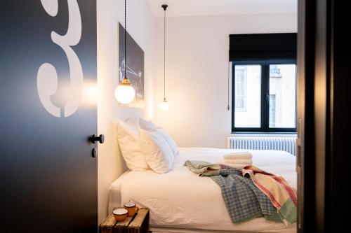 a bedroom with a bed with white sheets and a window at Espace 43 - Les 7 chambres in Namur