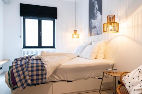 a bed in a white room with a window and lights at Espace 43 - Les 7 chambres in Namur