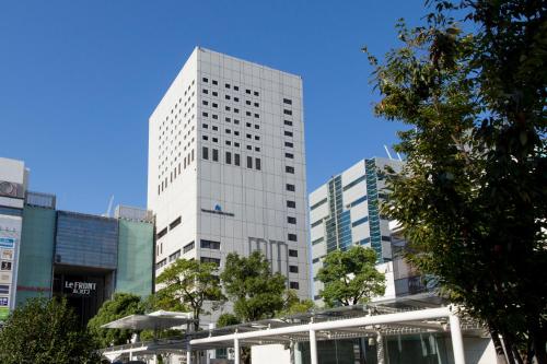 a tall white building in the middle of a city at Kawasaki Nikko Hotel in Kawasaki