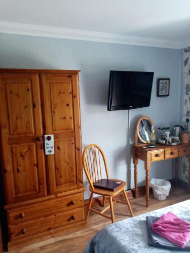 1 dormitorio con armario de madera, silla y escritorio en The Guest House, en Abergavenny