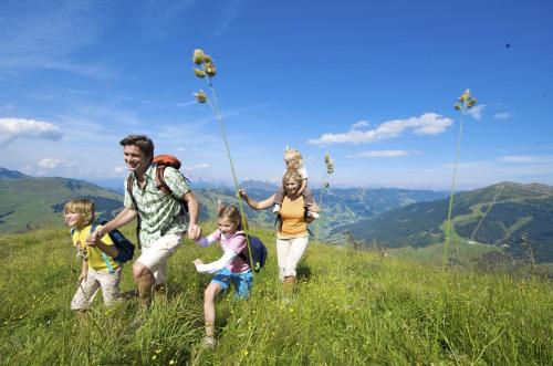 a group of people walking on a grassy hill at Johanneshof - Dein MOUNTAIN Wohlfühlhotel in Saalbach Hinterglemm